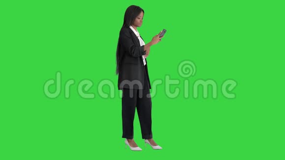 一位美丽的非裔美国女性对着手机微笑在绿色屏幕上用Chroma键拍摄自拍视频的预览图