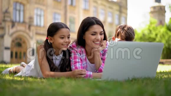 妈妈带着孩子在户外看动画片视频的预览图