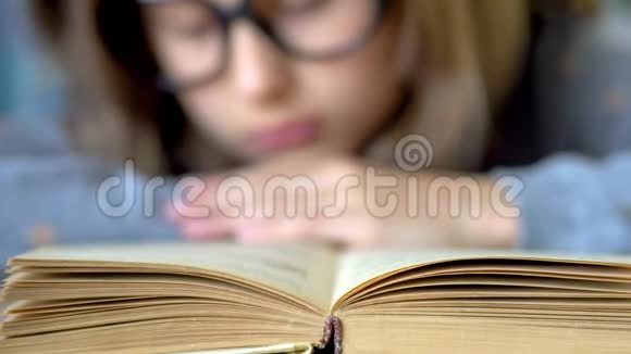 前景是一本书一个戴着大黑眼镜的女孩正在看书关闭视野视频的预览图