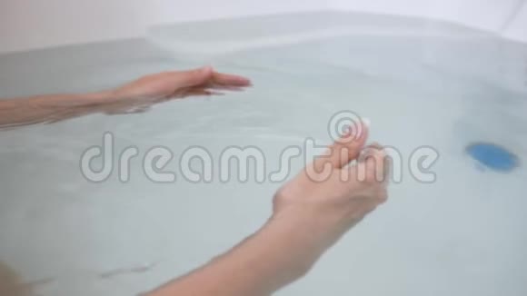 在装满水的浴缸里特写女人的手把他的双手扔进水里视频的预览图