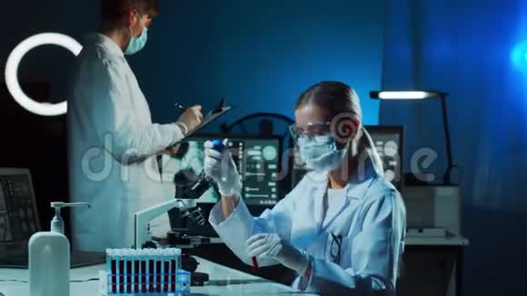 在实验室工作的医学科学家教授实习生进行血液分析研究的医生实验室工具显微镜视频的预览图