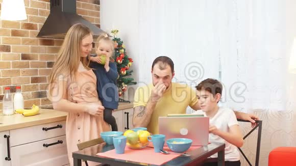 白种人可爱的家庭在家里在厨房里看笔记本电脑上的视频视频的预览图