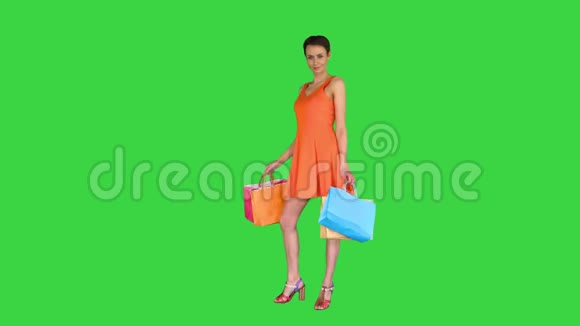 一个女人在镜头前摆姿势绿色屏幕上放着五颜六色的购物袋彩色键视频的预览图