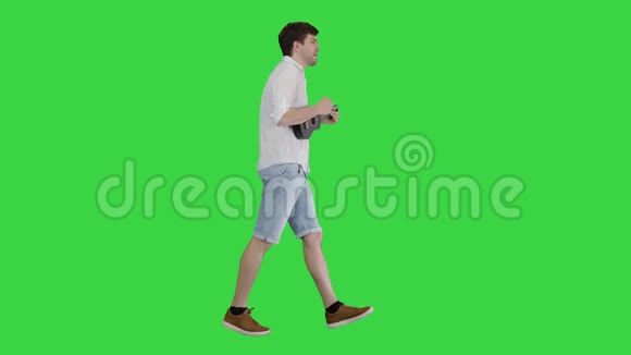 年轻人演奏四弦琴在绿色屏幕上唱歌和走路Chroma键视频的预览图