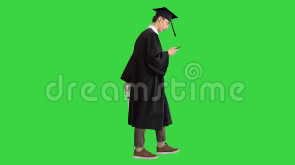 毕业典礼快乐的学生步行和短信在他的手机上的绿色屏幕铬键视频的预览图
