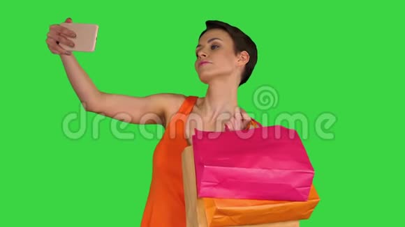 迷人的年轻女人拿着不同的空白购物袋在绿色屏幕上自拍铬钥匙视频的预览图
