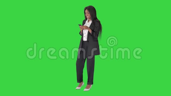 快乐的非裔美国年轻商务女性手握智能手机社交媒体应用程序在绿色屏幕上大笑视频的预览图