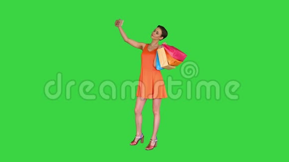 迷人的年轻女人拿着不同的空白购物袋在绿色屏幕上自拍Chroma键视频的预览图