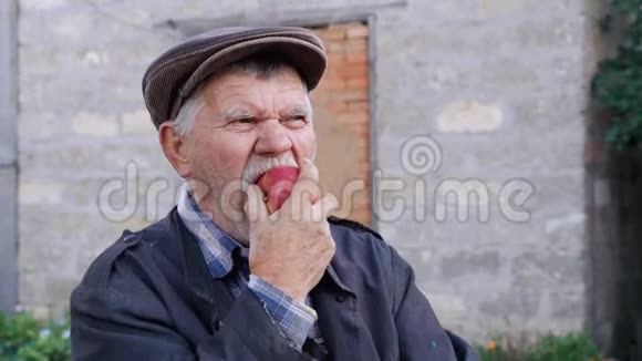 养老金领取者将过上健康的生活方式一位穿着旧夹克的乡下老汉努力咬一个成熟的红苹果视频的预览图