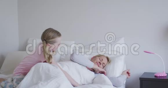 白种人女孩在床上叫醒母亲的侧视视频的预览图