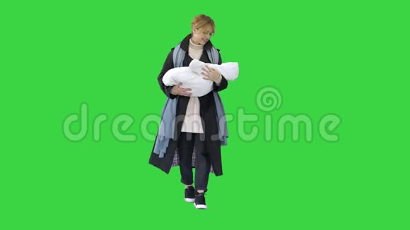 美丽的年轻母亲抱着她的孩子走在绿色的屏幕上铬钥匙视频的预览图