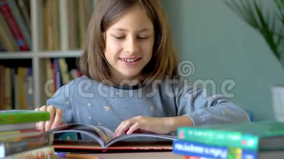 一个微笑的女孩坐在桌子旁在书中考虑插图关闭视野视频的预览图