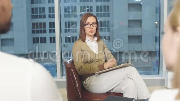 女性职业心理学家在笔记本上的谈话听力和写作笔记视频的预览图