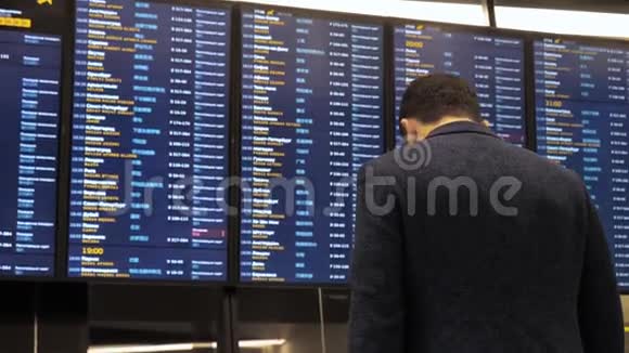 旅客在机场看时刻表板屏幕国际航班商务人员出国旅游视频的预览图