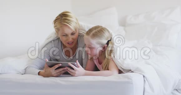 白种人妇女和她的女儿在床上使用数字平板电脑的正面视图视频的预览图