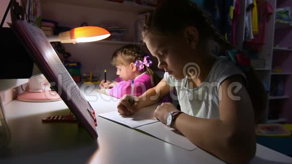 两个女孩在深夜做作业在台灯的灯光下视频的预览图