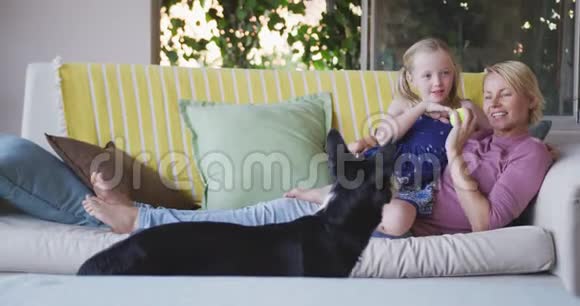 白种人女人和她的女儿在家玩狗的侧视图视频的预览图