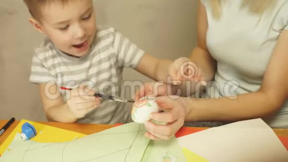 母亲教儿子如何装饰鸡蛋作为复活节庆祝活动的装饰视频的预览图