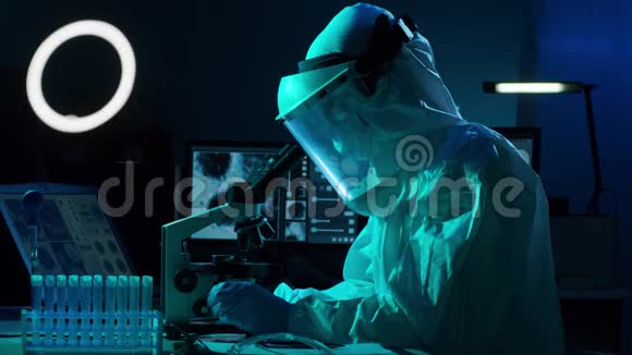 使用实验室设备在研究实验室工作的保护服和口罩的科学家显微镜试管视频的预览图