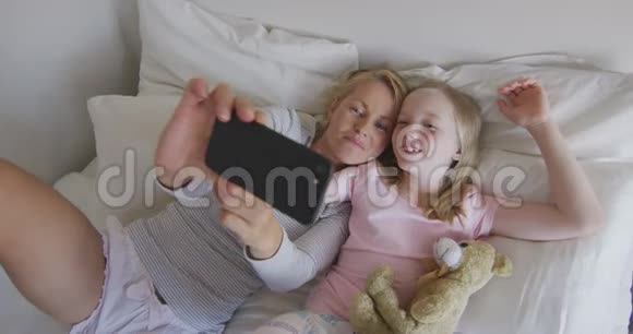 俯瞰白种人女人和她的女儿在床上自拍视频的预览图