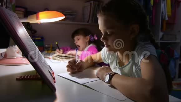 姐妹们在深夜做作业坐在桌子旁其中一个想睡觉打哈欠视频的预览图