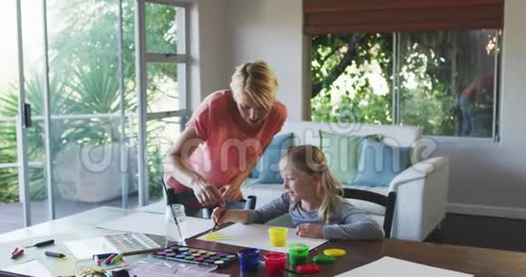 白种人妇女与女儿在家绘画的侧视图视频的预览图