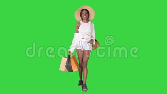 时尚年轻的非洲女人带着购物袋走在绿色屏幕上铬钥匙视频的预览图