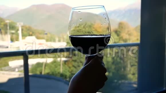 在窗外的背景上用美丽的山景特写女性手中酒杯的轮廓视频的预览图