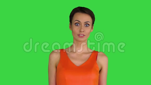 穿着橙色太阳裙的年轻女子在绿色屏幕上震惊或惊讶彩色键视频的预览图