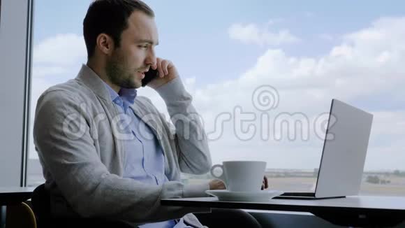 在电话里的商人坐在咖啡馆里用笔记本电脑工作视频的预览图