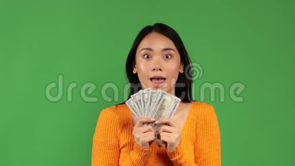 亚洲年轻女子手里拿着一捆钱微笑着手里拿着钱购物和购物的概念视频的预览图