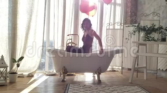 穿着晚礼服的优雅混搭女人带着气球走出浴缸视频的预览图