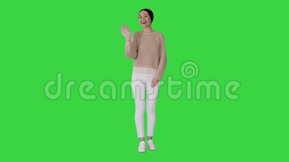 快乐的年轻女子挥动手在绿色屏幕上迎接你Chroma键视频的预览图