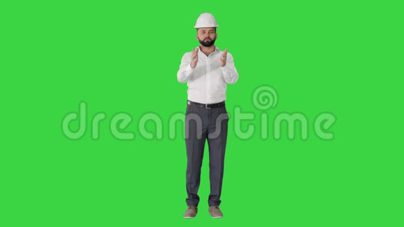 建筑工程师穿着白色衬衫和安全帽在绿色屏幕上与相机交谈色度键视频的预览图