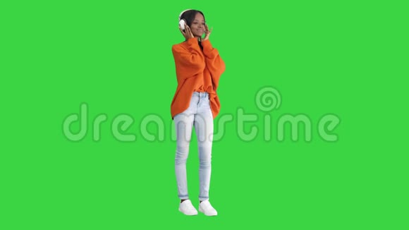 年轻的非洲妇女戴着耳机在绿色屏幕上欣赏音乐Chroma键视频的预览图