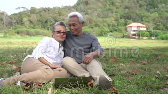 亚洲夫妇年长的老人退休后放松一下看着手提电脑技术视频的预览图