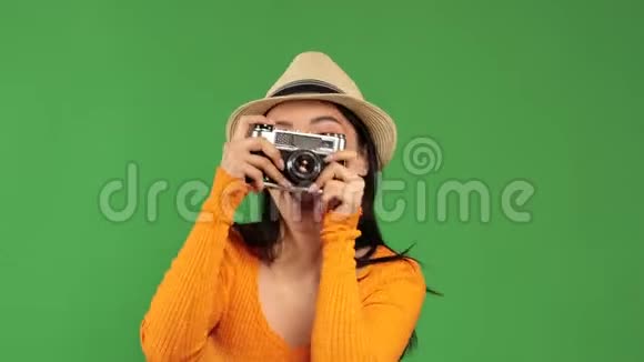 漂亮的亚洲女人穿着时尚的服装积极地通过绿色背景上的复古相机拍照爱好休闲视频的预览图