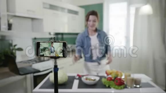 现代家庭主妇博主在智能手机上为vlog记录视频内容谈论适当的营养显示饮食计划视频的预览图