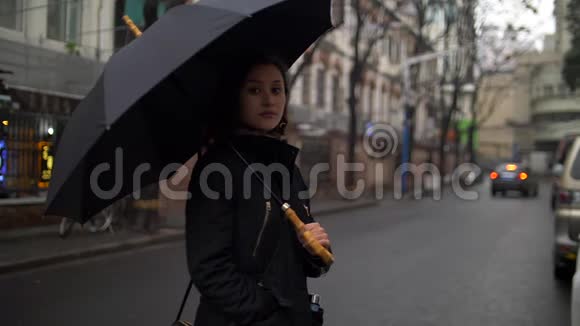 在寒冷的日子里街上带着雨伞的美丽的年轻女子视频的预览图
