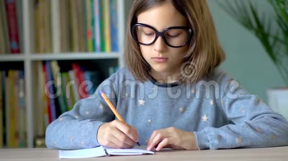 女孩用黄色的钢笔在笔记本上写字前景关闭视野视频的预览图