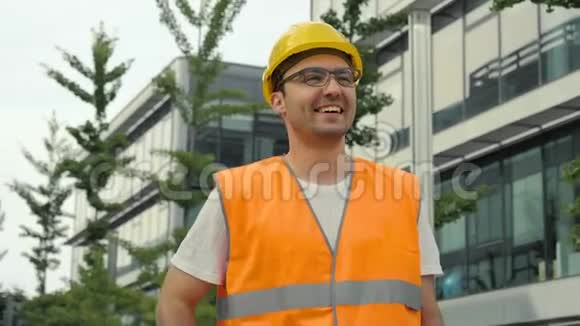 年轻的工程师戴着眼镜微笑着戴着安全帽对他的工作成果感到高兴视频的预览图
