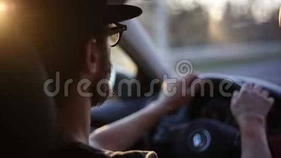小胡子司机特写双手驾驶汽车车轮戴眼镜戴黑帽与乘客交谈视频的预览图