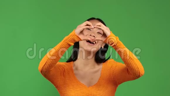 年轻的亚洲女人用她的双手显示出一颗微笑的心并把她的手按在自己身上幸福的概念视频的预览图