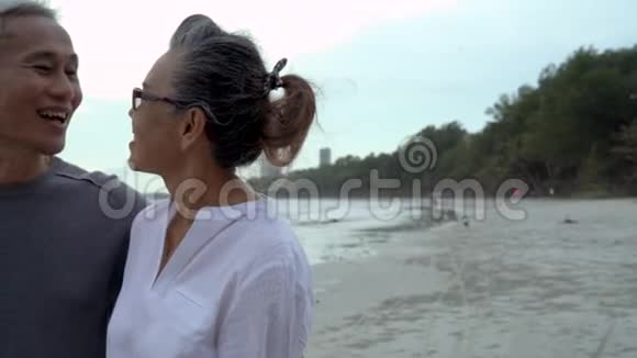 亚洲夫妇年长的老人退休后休息放松散步日落海滩蜜月视频的预览图