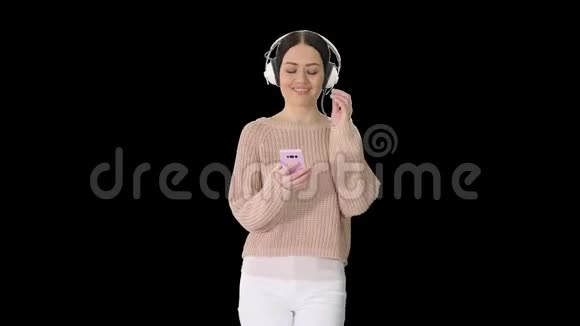 带着耳机听着智能手机听音乐的快乐女孩阿尔法频道视频的预览图
