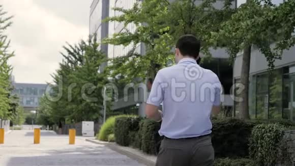 手机男年轻的商人穿着智能手机穿着智能休闲服装走路视频的预览图