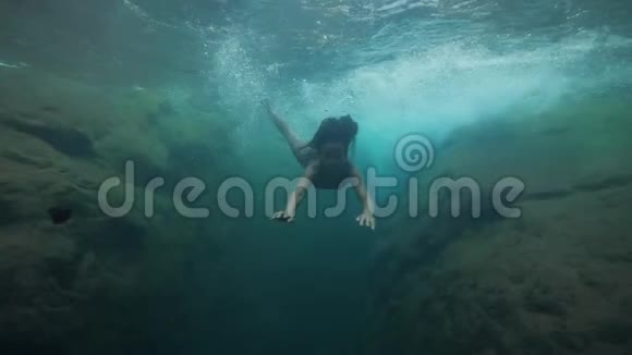 年轻漂亮的女人在泉水瀑布里水下游泳视频的预览图