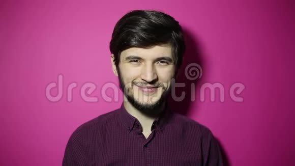 年轻微笑男子的肖像在粉红色背景上戴上青色太阳镜视频的预览图