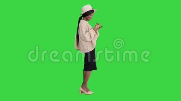 迷人的时尚打扮的女时髦女孩使用智能手机和笑在绿色屏幕Chroma键视频的预览图
