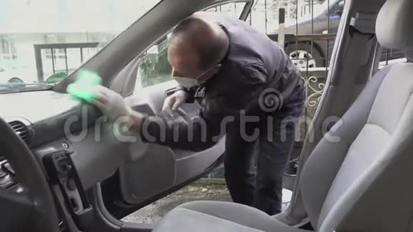 中年人用口罩和手套消毒汽车打扫车门视频的预览图